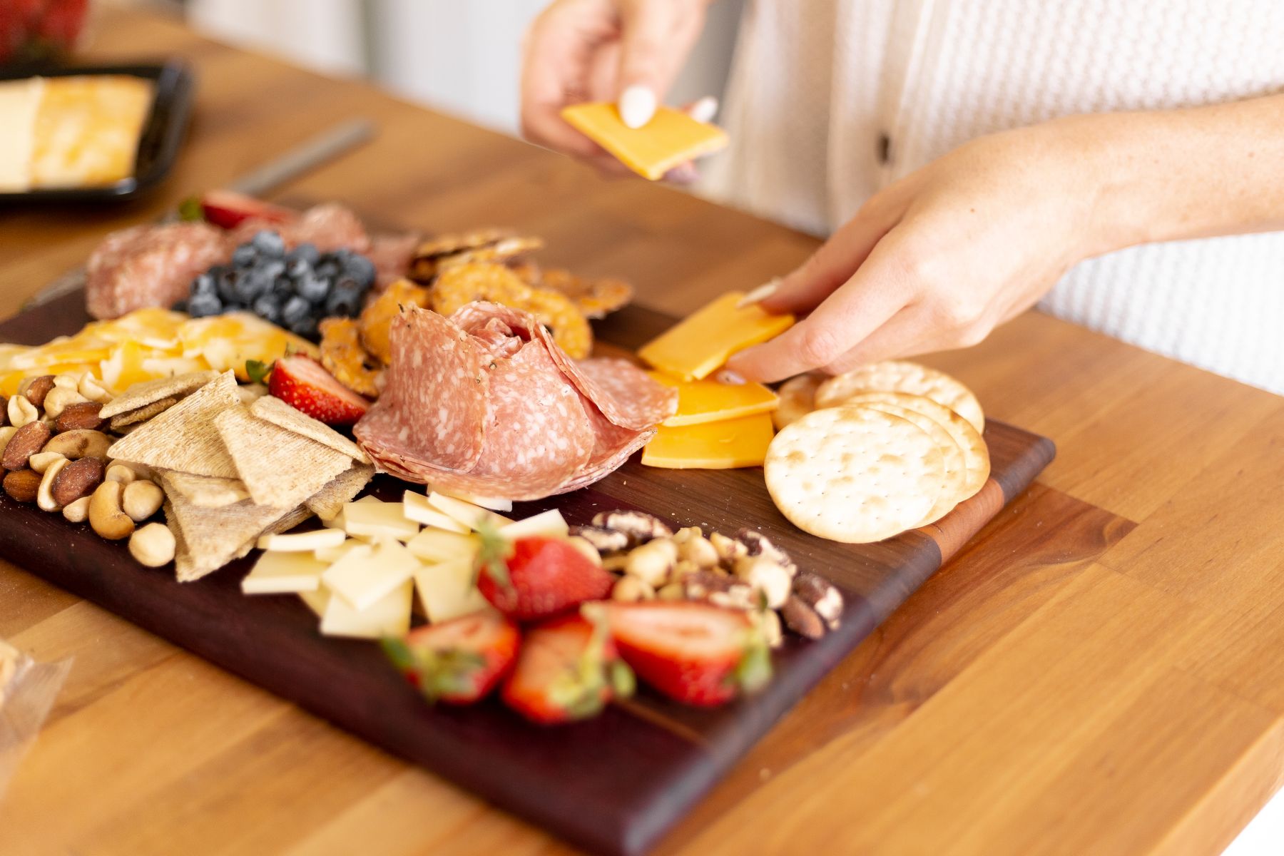 Hands arranging an abundant charcuterie board