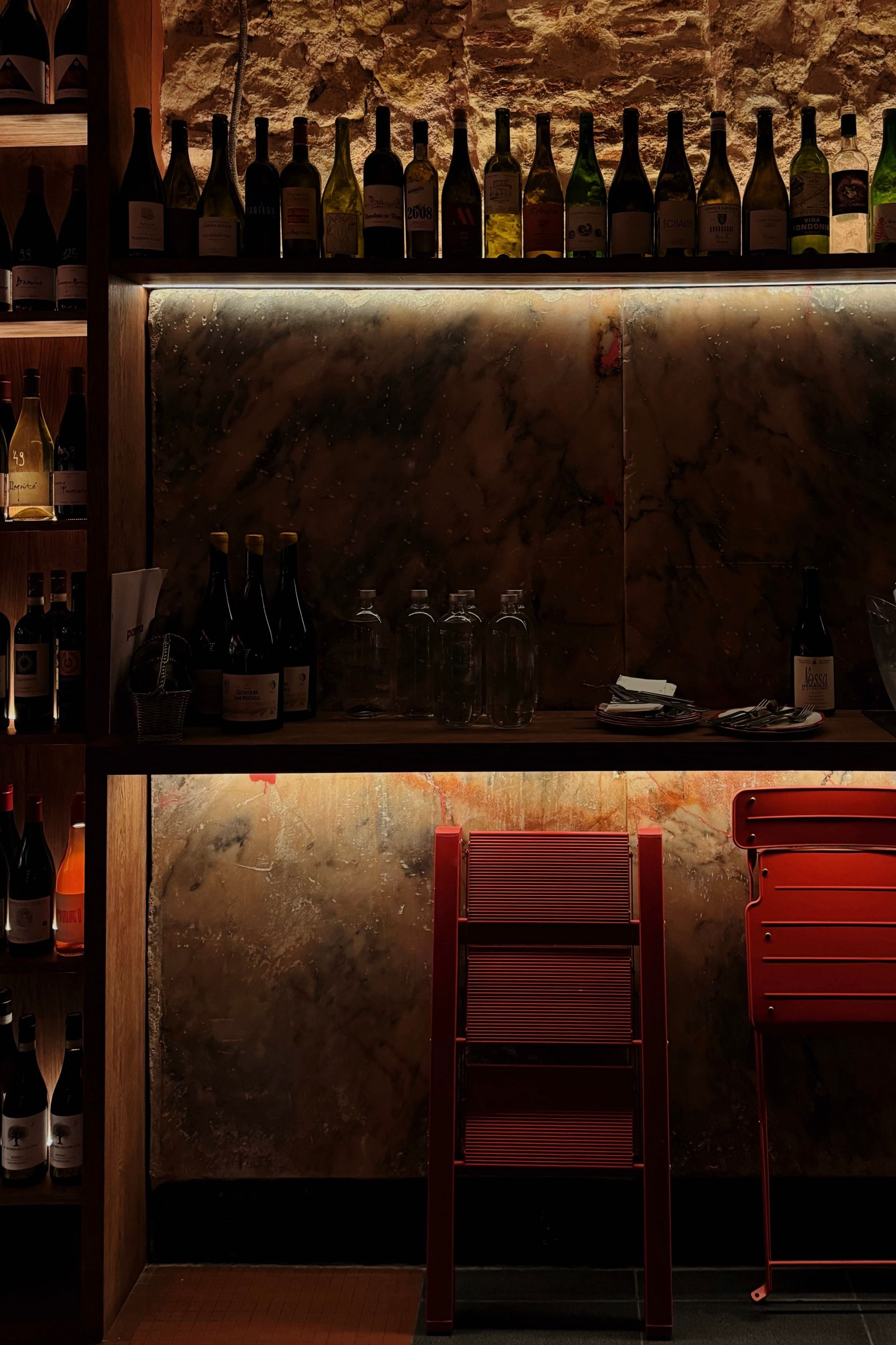 A warmly lit wine bar with bottle-lined shelves